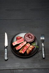 Grilled roated beef steaks on black ceramic plate