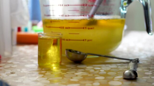 panning shot of girl wearing latex gloves blending oils using blender with a small glass bottle of aromatic oil for the process of home made natural artisanal soap making