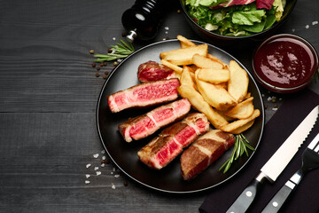 Grilled roated beef steaks on black ceramic plate