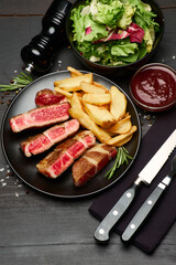 Grilled roated beef steaks on black ceramic plate