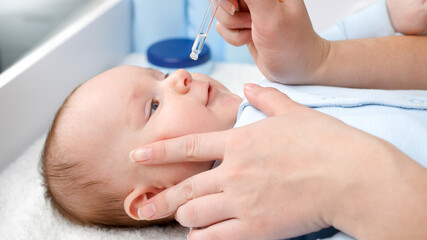 Curing baby with runny nose using medication in droplets from runny nose. Concept of child health,...