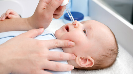 Obraz na płótnie Canvas Closeup of doctor giving coronavirus vaccine to newborn baby from eyedropper in hospital