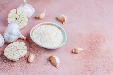 Bowl with dried garlic powder and garlic bulbs.