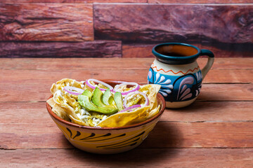 Mexican food. green chilaquiles with avocado, onion and cup of Mexican coffee