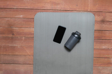 cell phone and sports shaker on yoga mat in gym studio