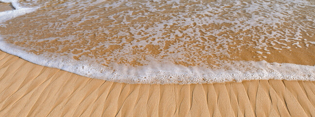 Soft wave of blue ocean on sandy beach. Wide photo.