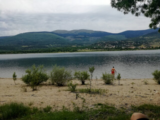 a person with a red bathing suit takes a bath in the river one day with clouds