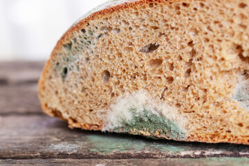 A slice of bread covered with mold on a wooden surface