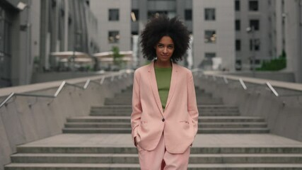 Charming young modern multiracial woman with black hair walking at the street and looking into the camera for photoshoot outdoors. Beauty, fashion and models concept.