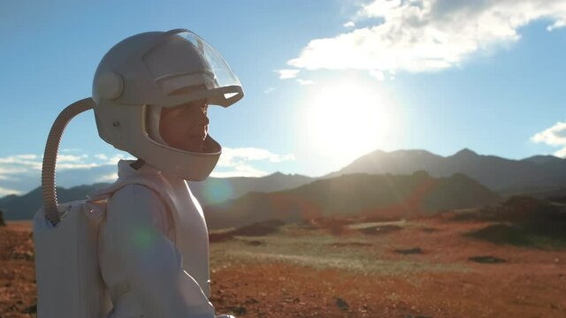 Little young happy child boy wearing astronaut uniform and helmet cosmonaut walking on Mars Red Planet sunset field. Space man, Kid big dream, childhood, freedom, travel, future, professions concept