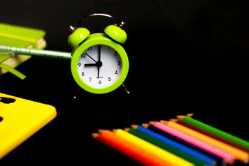 Back to school background with colored pencils and alarm clock. Concept with space for text or other elements on the subject of school and time management in elementary school.