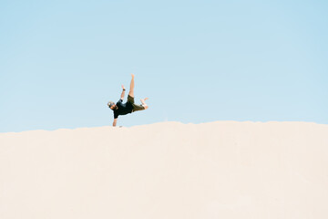 Young man doing handstand in the sand dunes. concept of holidays and freedom