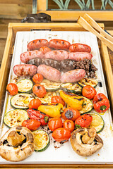 Grilled cherry tomatoes, red and yellow peppers, mushrooms, sausages, blood sausages, chorizo on a...