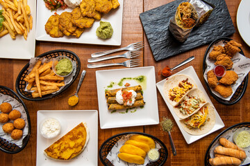 Top view image of Tex Mex and Venezuelan dishes. Tacos, tequenos, arepas, guacamoles, cachapa, croquette, patacones, golden tacos