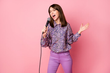 Photo portrait of woman singing holding microphone isolated on pastel pink colored background