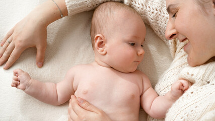 Portrait of little baby boy lying with mother on soft blanket in bed. Concept of parenting ,baby hygiene and child care