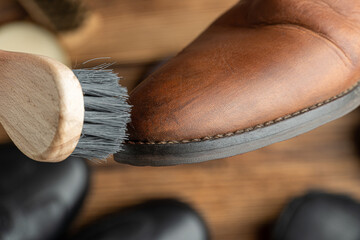 cleaning, polishing, restoration brown leather boots with brush and footwear care product, shoe polish