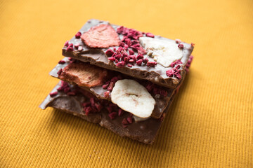 a bar of delicious milk chocolate with additions of dry raspberries and banana chips in place for the text in a bright yellow color