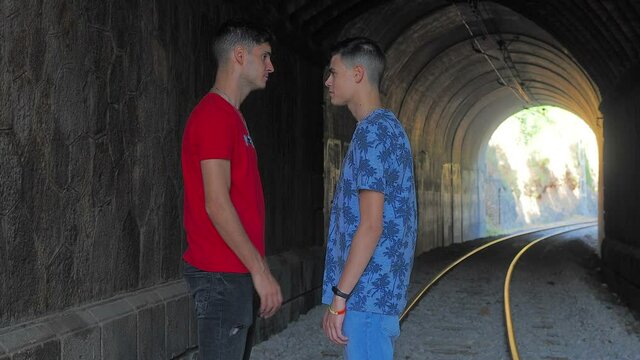 pareja gay paseando por las vías del tren entrando en un túnel y abrazándose con mucho cariño