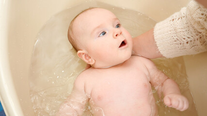 Closeup of mother supporting baby head while washing in bath. Concept of parenting ,baby care and healthcare