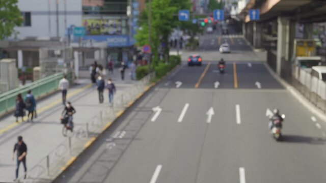歩道を移動する人々。道路を走る車。秋葉原。　ぼやけた動画。日本の風景。