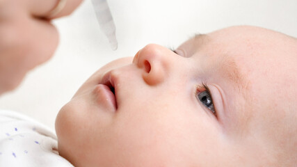 Giving vaccine or vitamins to baby from eyedropper. Concept of newborn babies healthcare and...