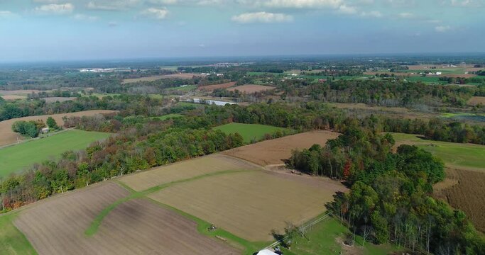 A wide aerial flyover of a typical Ohio farm. Camera tilts up to summer skyscape.	