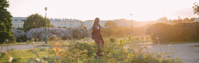 Portrait of a beautiful young woman in the park at sunset in summer.