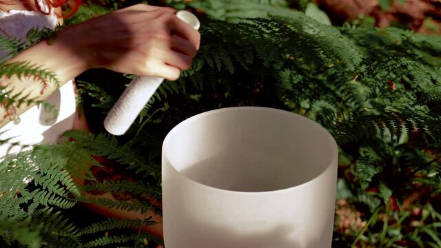 Hands playing on white quartz crystal singing bowls in the forest. Healing medicine and meditation Spiritual music Buddha Fern background