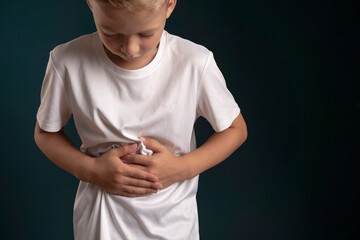abdominal pain in a child. poisoning in children. the boy holds his hands to the abdominal cavity