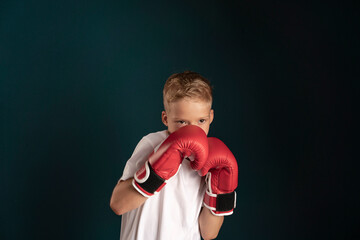 a young man in white clothes with blond hair boxing in red boxing gloves on a dark background. the...