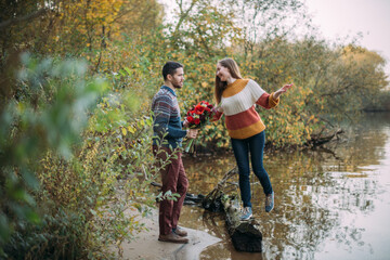 Naklejka na ściany i meble A romantic date, a walk in nature. Young couple of lovers together on the lake in early autumn