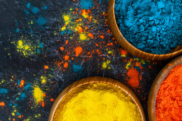Top view of colorful bright traditional holi paint powder in wooden bowls isolated on dark concrete background. Copy space for text. Happy holiday. Concept of Indian color festival called Holi.
