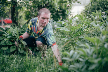 A man works in the garden, flying weeds, tending the lawn