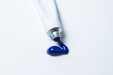 Squeeze out a tube of blue paint on a white background. Oil paint