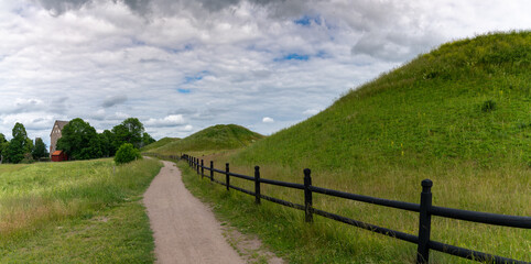 picturesque country landscape with a gravel path along grassy hills and a long brown wooden fence