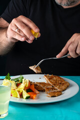 male hand eating from big dish German schnitzel with salad