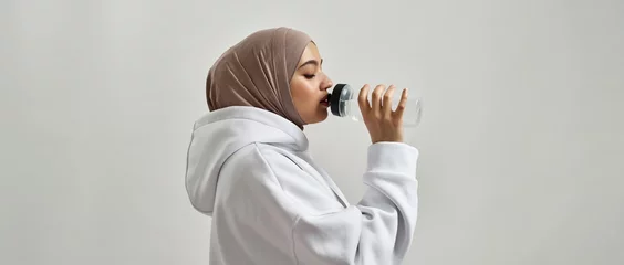 Foto op Plexiglas Portrait of young arabic girl in hijab drinking water © Svitlana