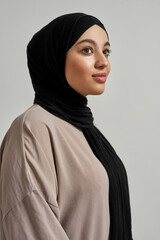 Happy young arabic woman in black hijab posing sideways