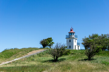 Fototapeta na wymiar view of the Hundested lighthouse on ist grassy hill under a blue sky