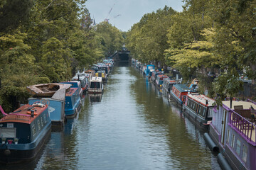 Rows of houseboats and narrow boats on the Regent's canal on Maida Avenue, Little Venice, West London, on a bright fall day.