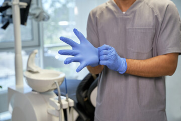 Medical worker using disposable gloves at dental clinic