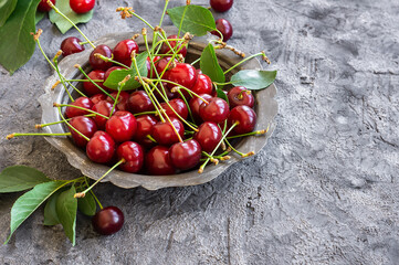 Fresh ripe sour cherry fruits in bowl on rustic table, red summer fruits