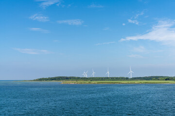 Fototapeta na wymiar landscape view of open ocean and shoreline with white wind turbines