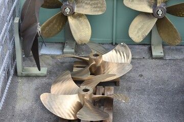 Ships’ or boats’ brass propellers with five blades exposed in the yard of shipyard or repair...
