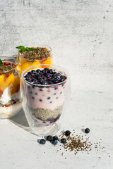 Fototapeta na wymiar Sliced fruit desserts in glass jar. Organic sweet chia seed pudding, blueberries, fruit breakfast. Vegan food
