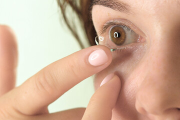 A young woman puts on lenses for vision, close-up