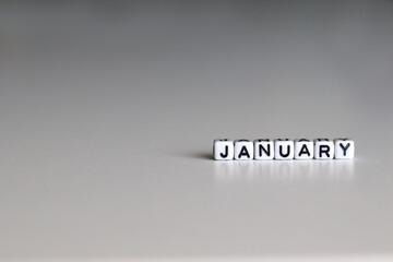 The text is written on white cubic blocks. The letters of the name of the month are written on the cubes in black letters highlighted on the glass surface. JANUARY text for your design.