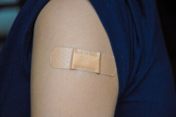 Close up on a teenager arm with a patch after vaccination for covid-19