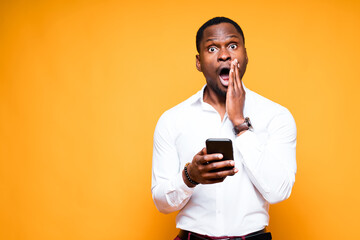 Handsome african american businessman holding a phone in his hand and looking at the camera in...
